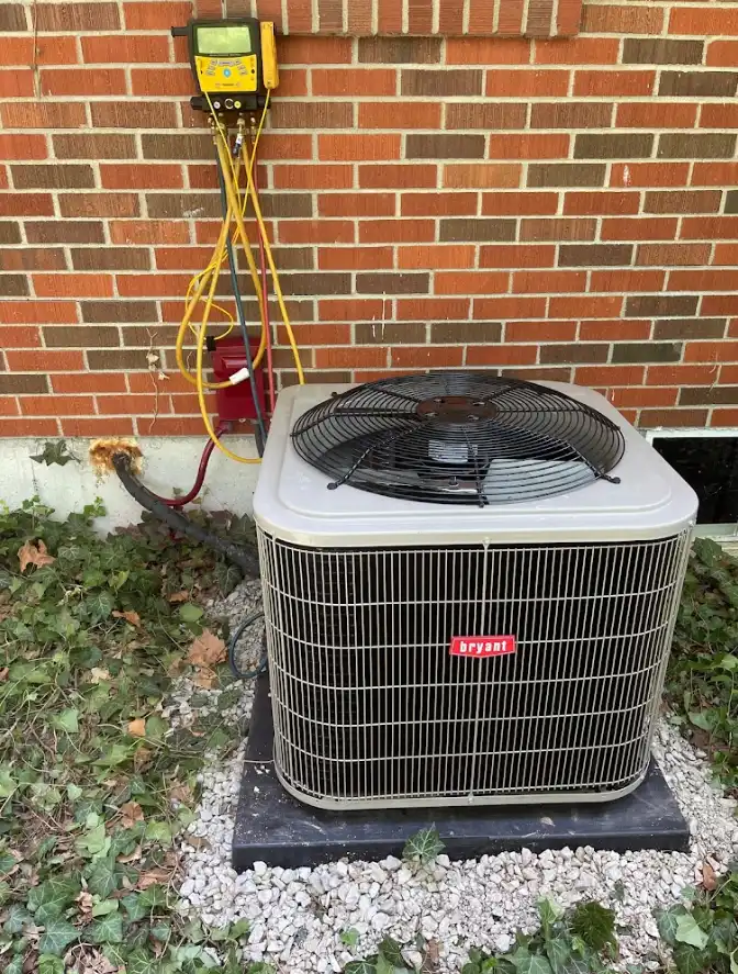 A Bryant heat pump undergoing professional heat pump maintenance with gauges attached for system testing outside a brick home.