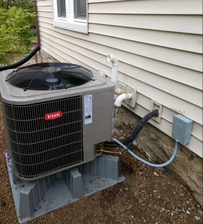 Heat pump installation showing an outdoor unit securely mounted against a house, demonstrating efficient setup and compact design.